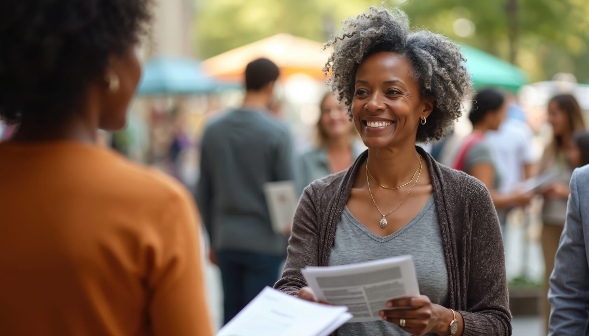 Smiling woman shares health information at community event. Offers pamphlets, resources, promoting wellness, education. People gather for advice, support at public health fair. Scene emphasizes