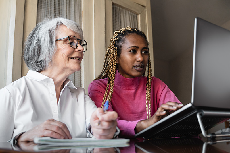 young woman helping elderly woman on a laptop